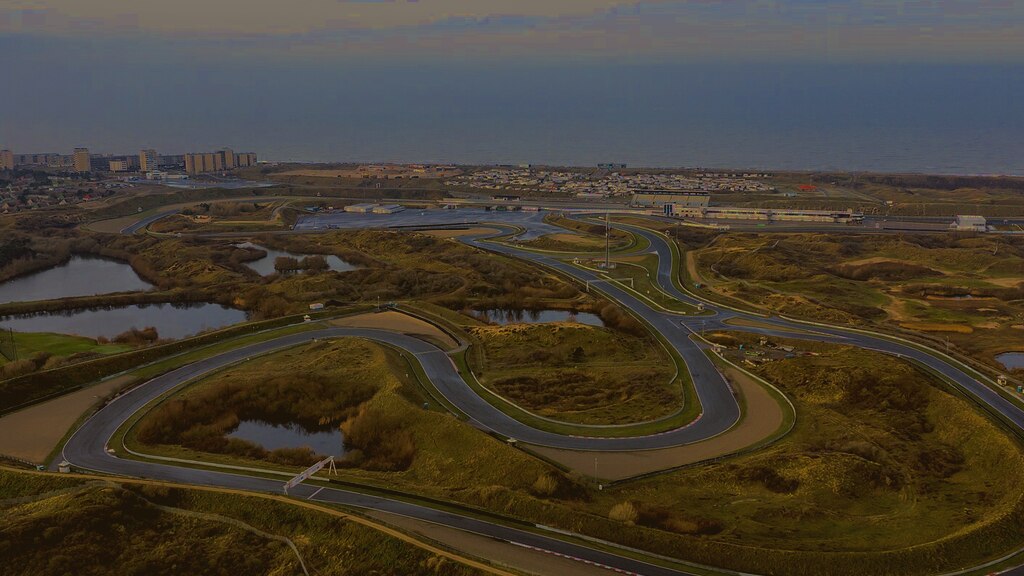 Aerial view of Circuit Zandvoort winding through the coastal dunes, with the North Sea beyond